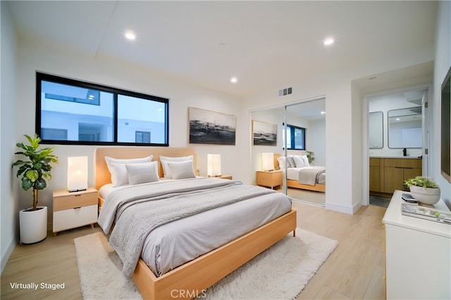 bedroom featuring ensuite bath, a closet, and light wood-type flooring