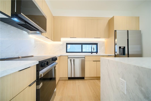 kitchen featuring appliances with stainless steel finishes, tasteful backsplash, sink, light brown cabinets, and light hardwood / wood-style flooring