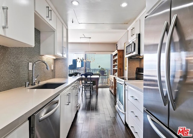 kitchen with white cabinets, appliances with stainless steel finishes, tasteful backsplash, sink, and hanging light fixtures