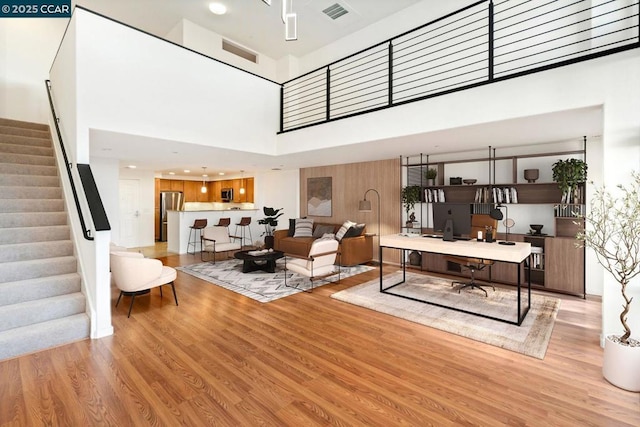 living room with a towering ceiling and light hardwood / wood-style floors