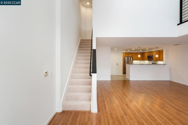 staircase featuring a high ceiling and wood-type flooring