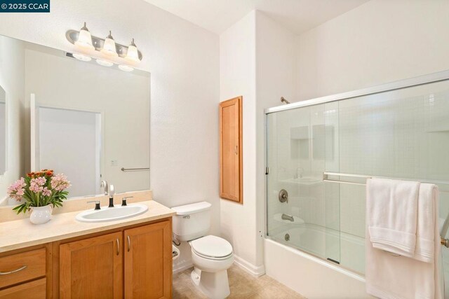 full bathroom featuring vanity, tile patterned flooring, bath / shower combo with glass door, and toilet