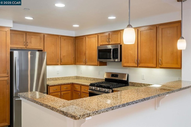 kitchen featuring a breakfast bar area, light stone counters, hanging light fixtures, appliances with stainless steel finishes, and kitchen peninsula