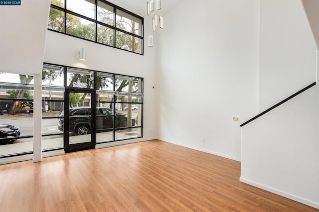 unfurnished living room with light hardwood / wood-style floors and a high ceiling