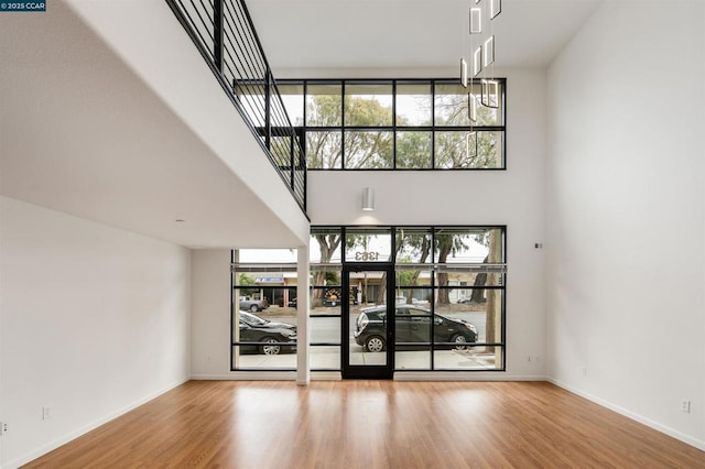 unfurnished living room with hardwood / wood-style floors, a wealth of natural light, and a high ceiling