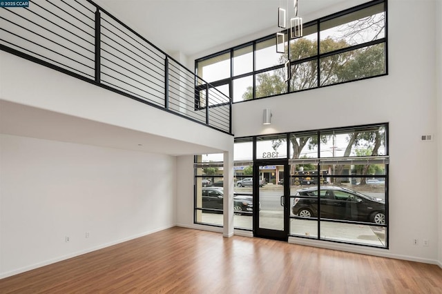 unfurnished living room featuring hardwood / wood-style flooring and a towering ceiling