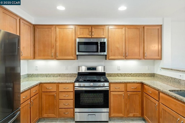 kitchen with appliances with stainless steel finishes and light stone counters