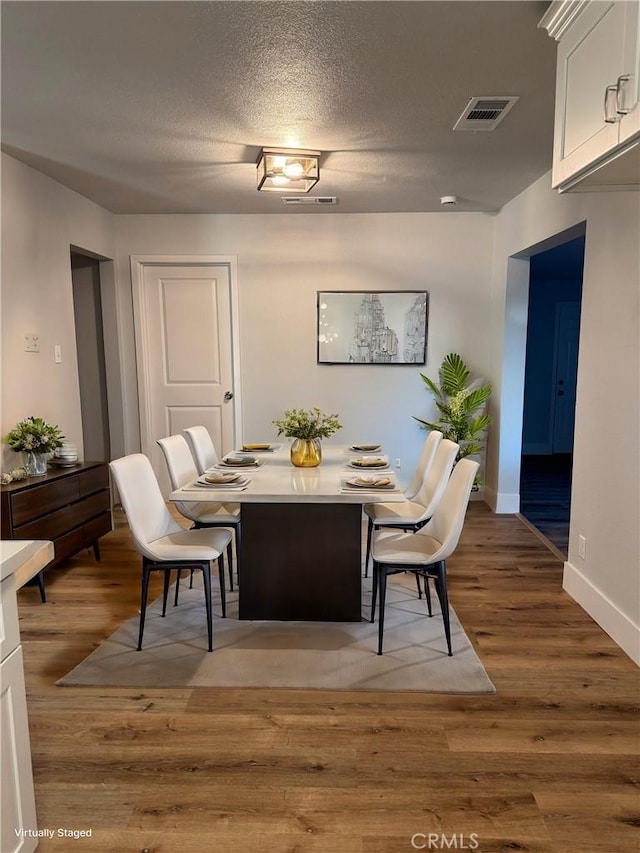 dining space featuring a textured ceiling and light hardwood / wood-style flooring