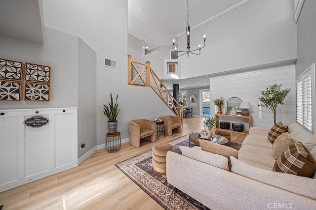 living room featuring a high ceiling, light wood-type flooring, and a notable chandelier