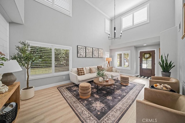 living room featuring a towering ceiling, an inviting chandelier, ornamental molding, and a healthy amount of sunlight