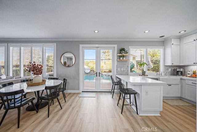 kitchen with white cabinets, french doors, a kitchen breakfast bar, decorative backsplash, and a kitchen island