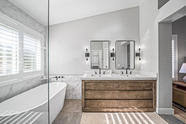 bathroom featuring a bath, tile walls, and vanity