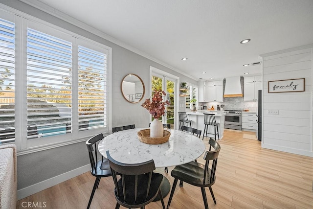 dining space with light hardwood / wood-style floors and crown molding