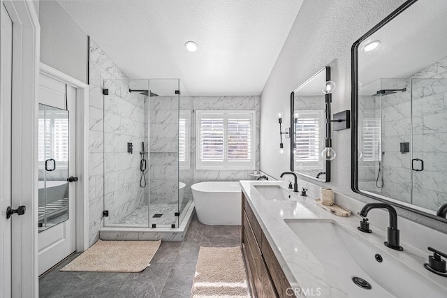 bathroom with a textured ceiling, shower with separate bathtub, and vanity