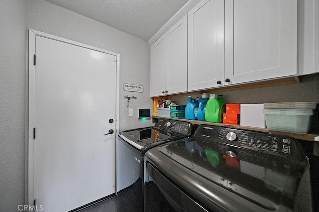 washroom with washer and dryer, a textured ceiling, and cabinets