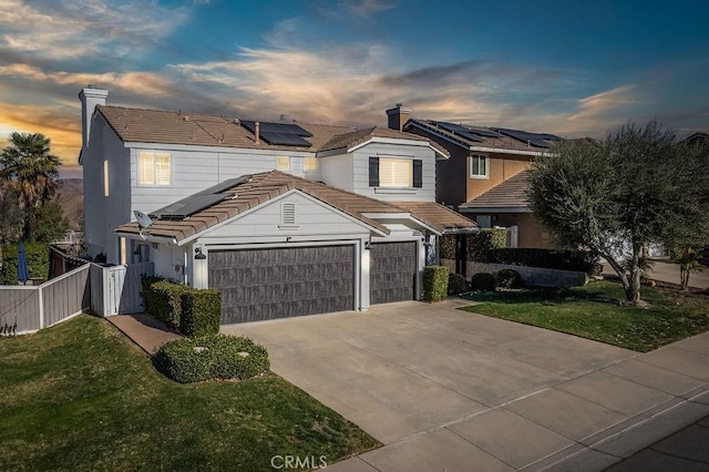 view of front of home featuring a lawn, a garage, and solar panels