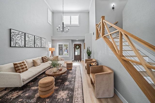 living room with a high ceiling, light wood-type flooring, crown molding, and a chandelier