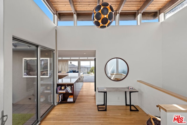 interior space with a healthy amount of sunlight, light wood-type flooring, beam ceiling, and wooden ceiling