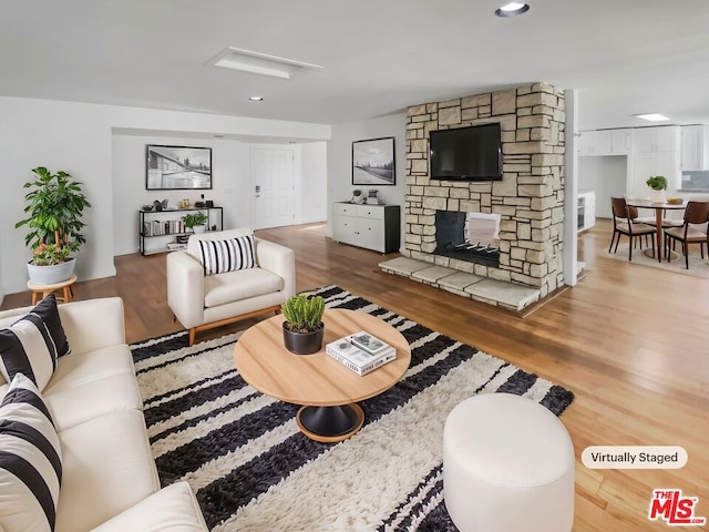 living room featuring a stone fireplace and wood-type flooring