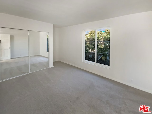 unfurnished bedroom featuring light colored carpet and a closet