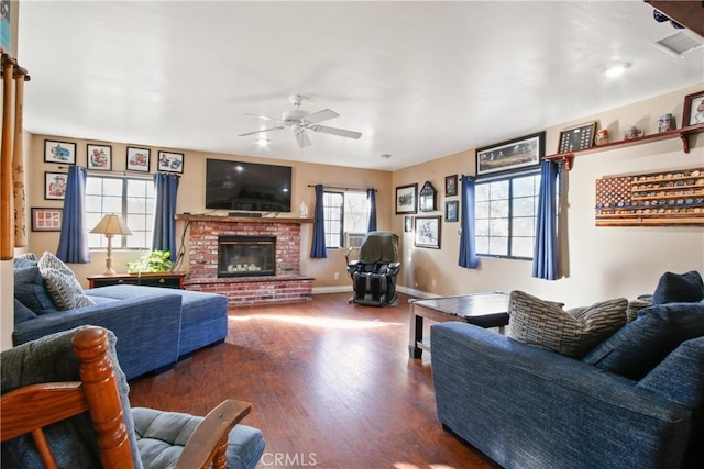 living room with a brick fireplace, ceiling fan, and dark wood-type flooring