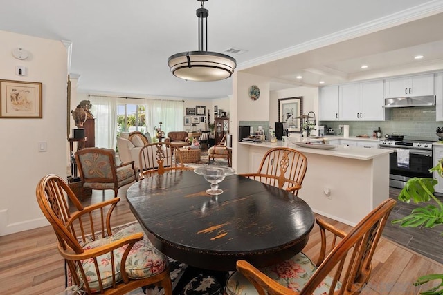 dining area featuring light hardwood / wood-style floors, crown molding, and a tray ceiling