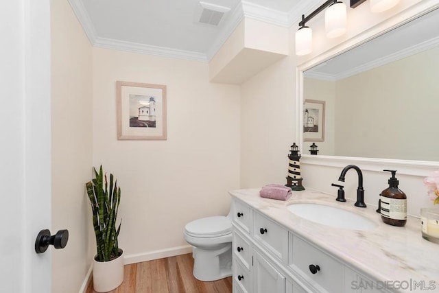 bathroom featuring toilet, ornamental molding, vanity, and hardwood / wood-style floors