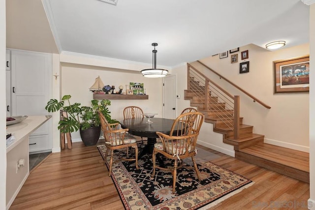 dining area with light hardwood / wood-style floors and ornamental molding