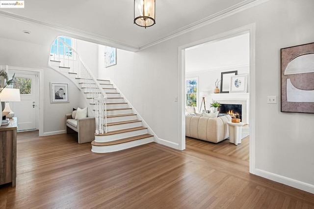 staircase featuring an inviting chandelier, crown molding, and hardwood / wood-style floors