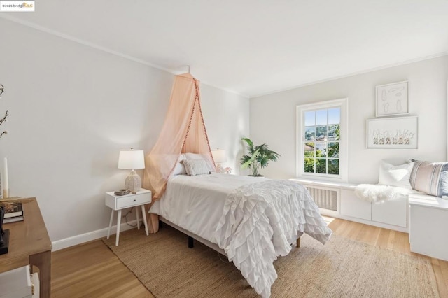 bedroom with radiator, light wood-type flooring, and crown molding