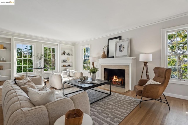 living room with a wealth of natural light, ornamental molding, hardwood / wood-style floors, and built in shelves