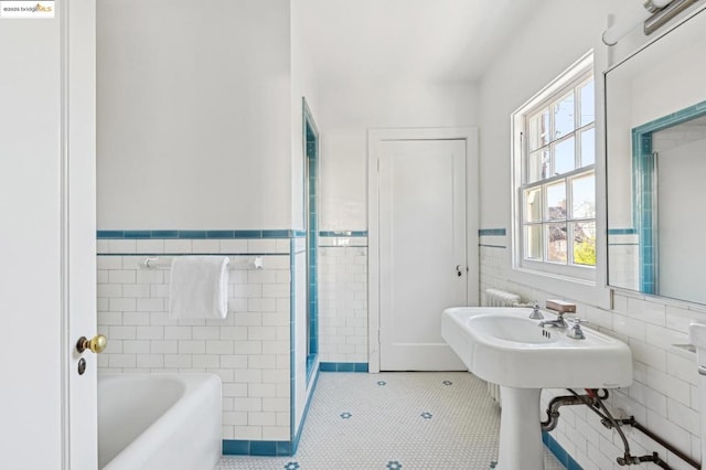 bathroom featuring a washtub, tile walls, and tile patterned floors