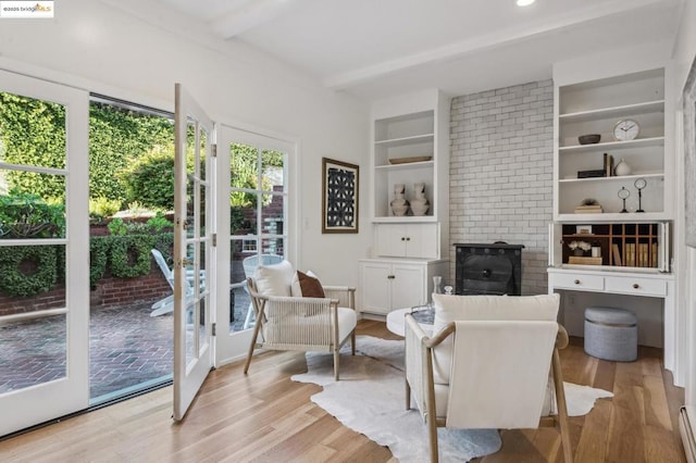 living area with a baseboard heating unit, built in features, french doors, and light hardwood / wood-style flooring