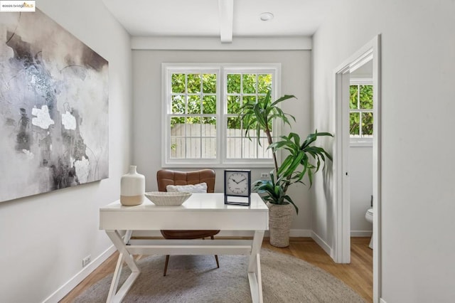 office with beam ceiling and light hardwood / wood-style flooring