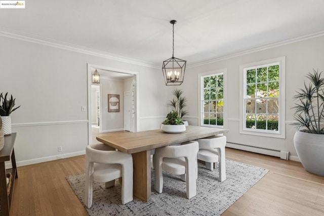 dining area featuring light wood-type flooring, a baseboard heating unit, an inviting chandelier, and ornamental molding