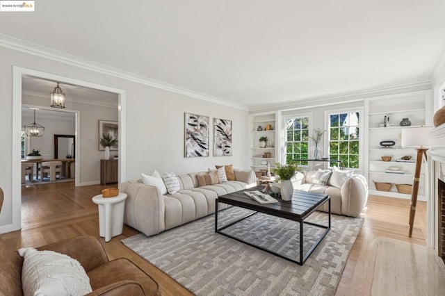 living room with built in features, crown molding, and a chandelier