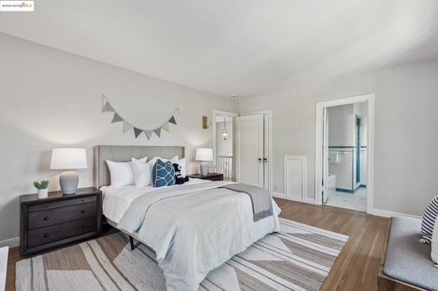 bedroom with wood-type flooring and ensuite bath