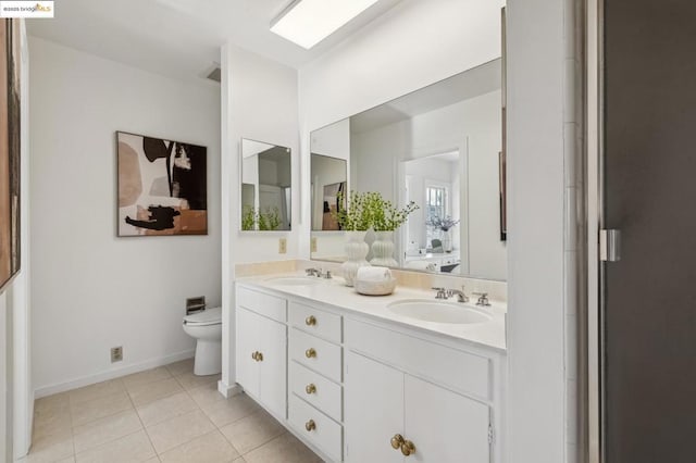 bathroom with toilet, vanity, and tile patterned flooring