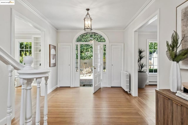 entryway featuring light hardwood / wood-style floors, radiator, ornamental molding, baseboard heating, and a chandelier