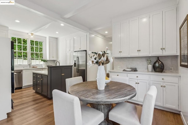 kitchen with stainless steel appliances, backsplash, white cabinets, and beamed ceiling