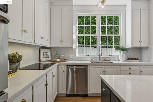 kitchen with light stone countertops, white cabinets, tasteful backsplash, sink, and black electric cooktop