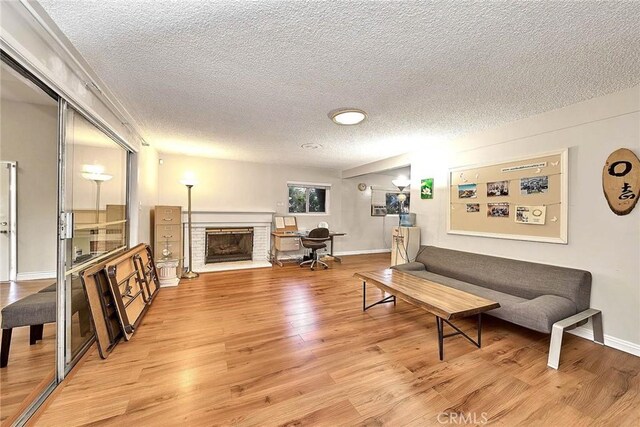 living room featuring light hardwood / wood-style floors, a textured ceiling, and a fireplace