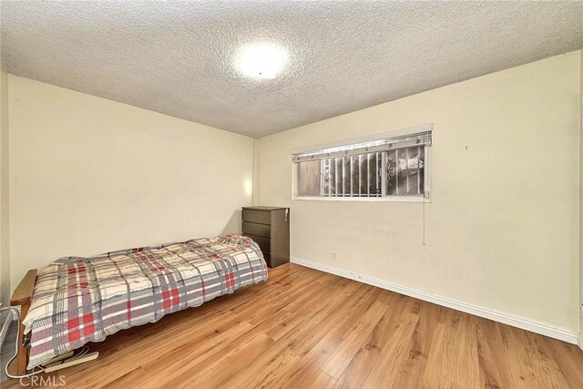 bedroom with a textured ceiling and light hardwood / wood-style flooring