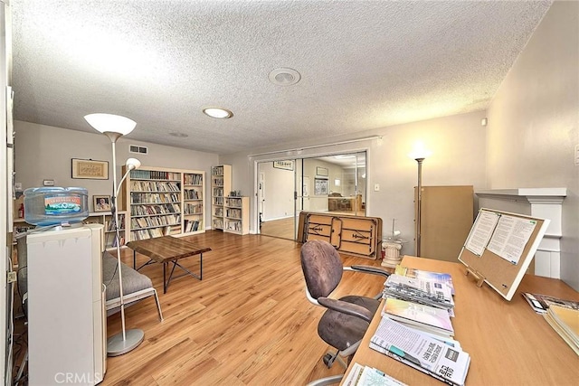 home office featuring light hardwood / wood-style floors and a textured ceiling