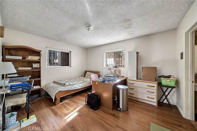 bedroom with a textured ceiling and wood-type flooring