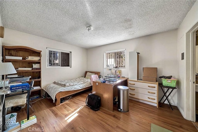 bedroom with hardwood / wood-style floors and a textured ceiling