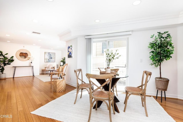 dining area with light wood-type flooring and ornamental molding