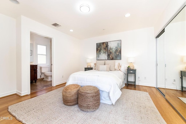 bedroom with ensuite bathroom, a closet, and hardwood / wood-style flooring