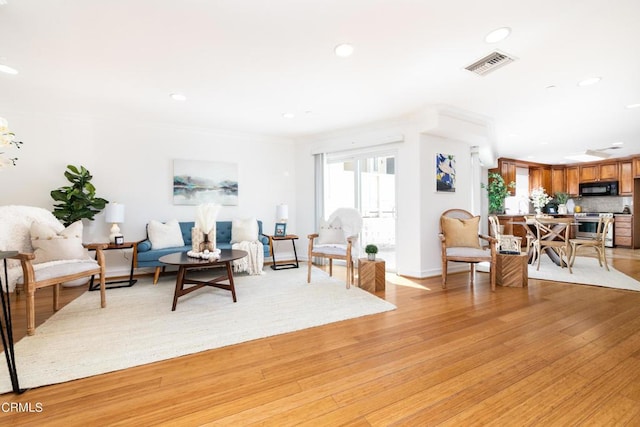 living room featuring light hardwood / wood-style floors and crown molding