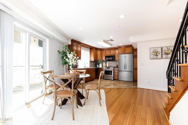 dining space with sink, light wood-type flooring, and crown molding